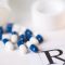 blue-and-white capsules spilling from a prescription medicine bottle across the corner of a prescription