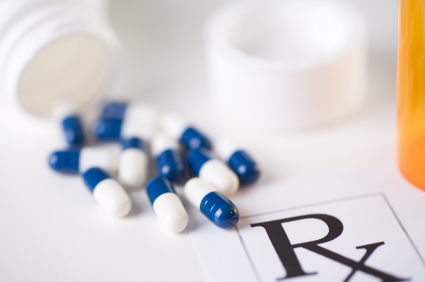 blue-and-white capsules spilling from a prescription medicine bottle across the corner of a prescription